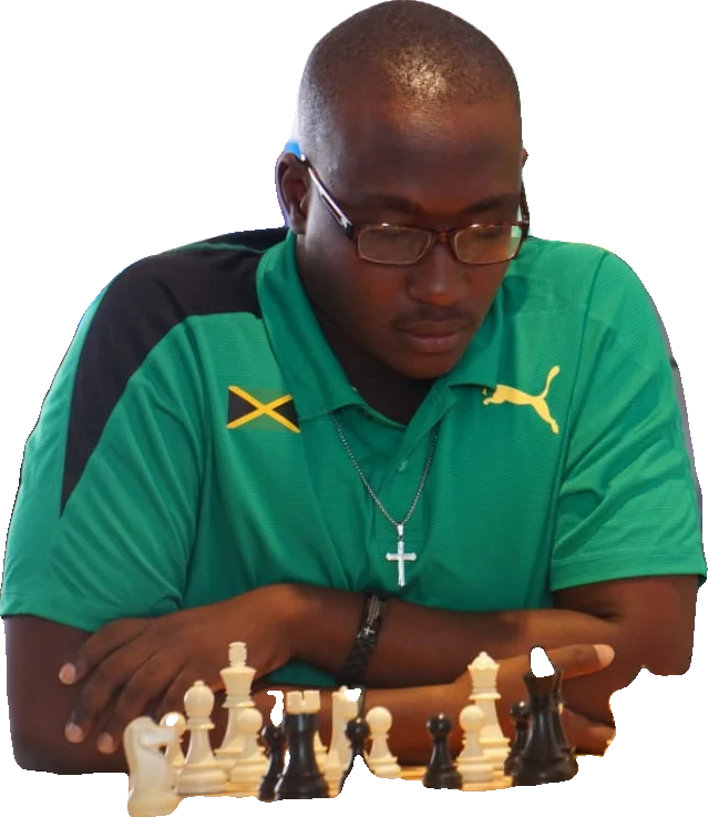 FM Shreyas Smith concentrating over a chess board in a Jamaica polo