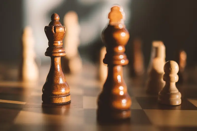 A wooden chessboard set up with the pieces in their starting position, ready for the opening moves.