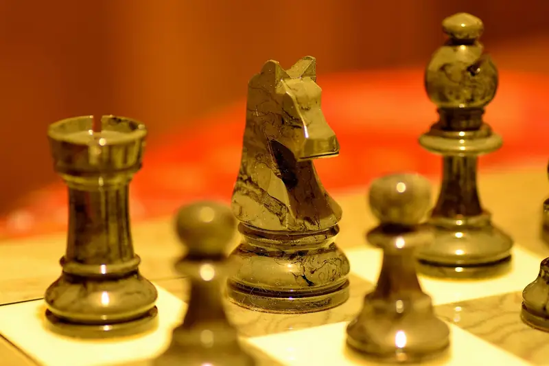 A black chess rook beside a knight and bishop on the board, highlighting the rook in the endgame.