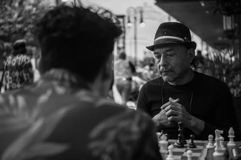 Two players facing each other across a chessboard in a focused, competitive tournament setting.